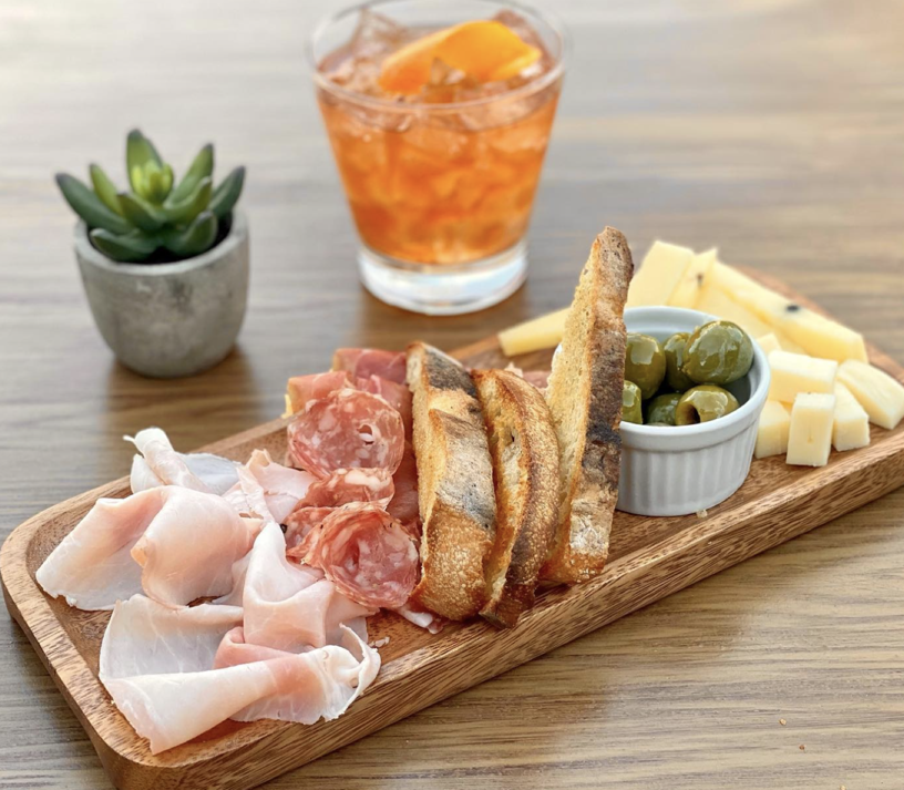 Tavola board with cured meats, cheeses, olives, and crostini